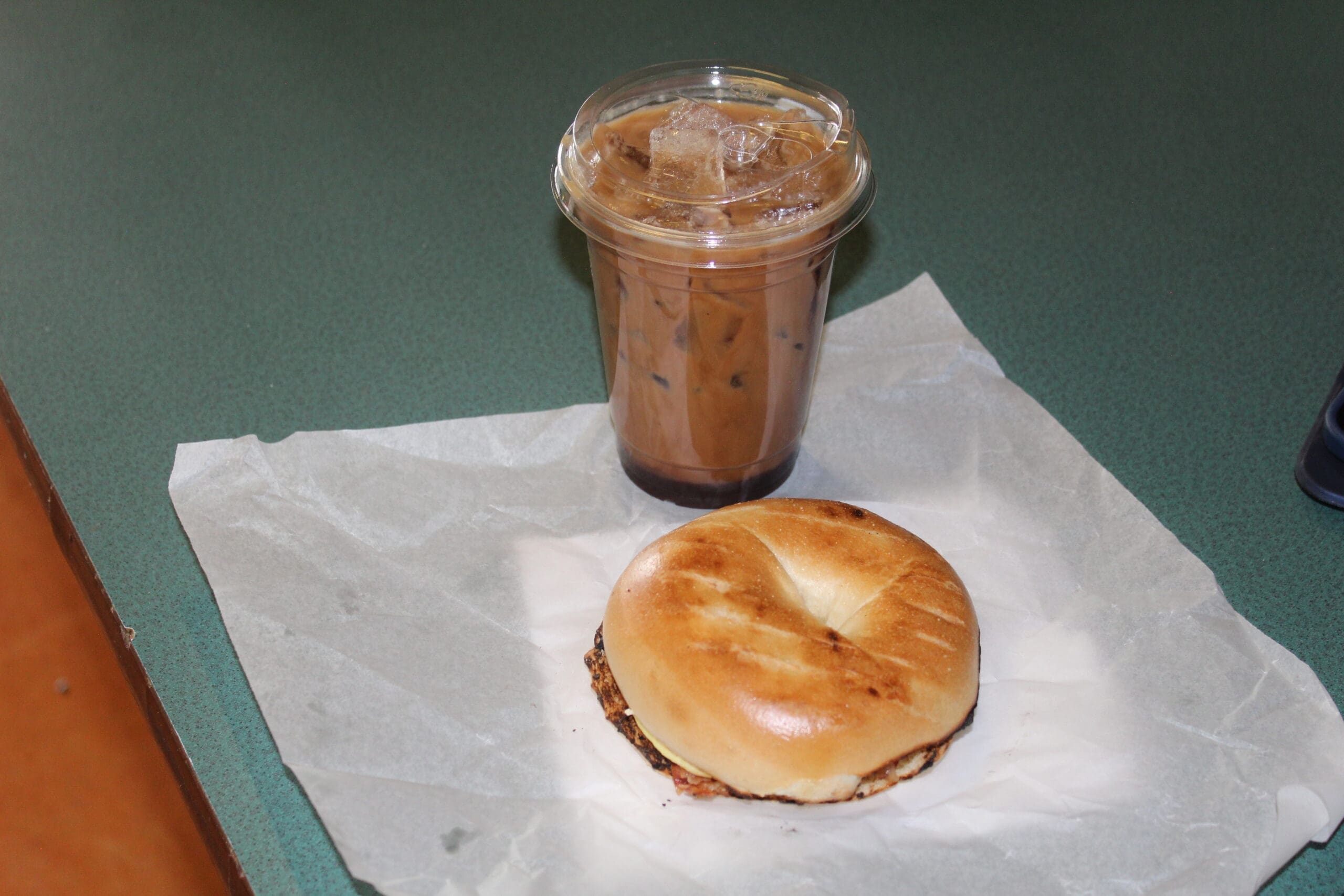 A sandwich sits beside an iced coffee